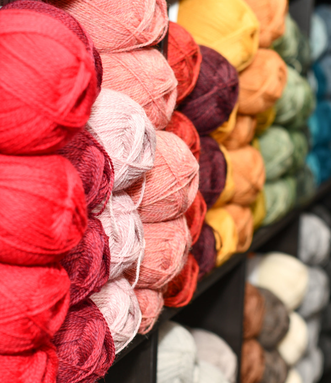 Brightly colored balls of yarn stacked by color in cubbies